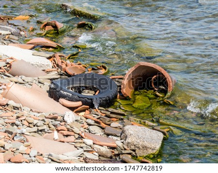 An abandoned old automobile tire polluting a rocky beach