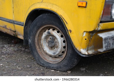 Abandoned, Old Car On The Street. Deflated Wheels., Close-up. Rust And Holes In The Body. Side View