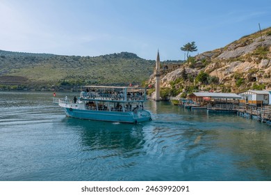 Abandoned old town view in Halfeti Town of Sanliurfa Province. Halfeti village and its submerged minaret and Turkish flags of toursit boats