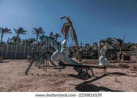 Abandoned playground on the beach. Sunny summer day. Broken swing. Empty playground.