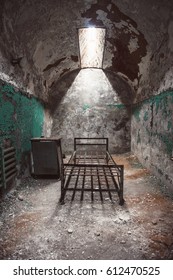 Abandoned Prison Cell Room With Old Rusty Bed Frame And Peeling Walls. Philadelphia Eastern State Penitentiary.
