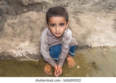 Abandoned Refugee Boy Drinking Water From River And Clothes Are Dirty And His Eyes Are Full Of Pain