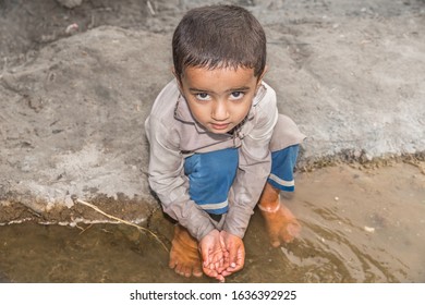 Abandoned Refugee Boy Drinking Water From River And Clothes Are Dirty And His Eyes Are Full Of Pain