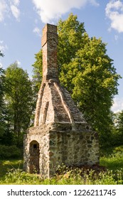 Abandoned Ruin Of Oven Chimney. Broken Furnace. Green Meadow Environment And Blue Sky Background