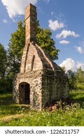 Abandoned Ruin Of Oven Chimney. Broken Furnace. Green Meadow Environment And Blue Sky Background