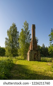 Abandoned Ruin Of Oven Chimney. Broken Furnace. Green Meadow Environment And Blue Sky Background