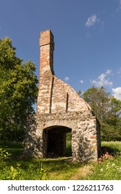 Abandoned Ruin Of Oven Chimney. Broken Furnace. Green Meadow Environment And Blue Sky Background