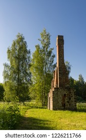 Abandoned Ruin Of Oven Chimney. Broken Furnace. Green Meadow Environment And Blue Sky Background