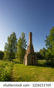 Abandoned Ruin Of Oven Chimney. Broken Furnace. Green Meadow Environment And Blue Sky Background