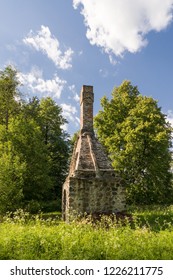 Abandoned Ruin Of Oven Chimney. Broken Furnace. Green Meadow Environment And Blue Sky Background