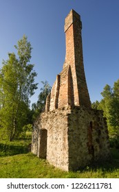 Abandoned Ruin Of Oven Chimney. Broken Furnace. Green Meadow Environment And Blue Sky Background