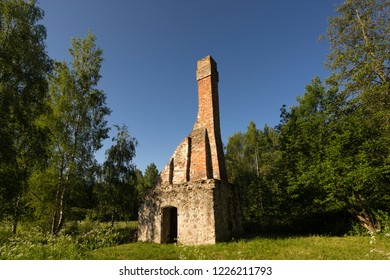 Abandoned Ruin Of Oven Chimney. Broken Furnace. Green Meadow Environment And Blue Sky Background