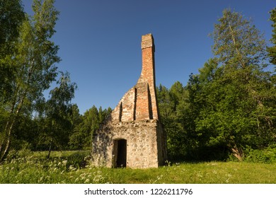 Abandoned Ruin Of Oven Chimney. Broken Furnace. Green Meadow Environment And Blue Sky Background