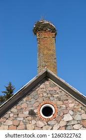 Abandoned Ruin Of Oven Chimney. Broken Furnace. Snowy Roof, Stork Slot And Blue Sky Background In The Winter