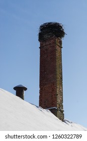 Abandoned Ruin Of Oven Chimney. Broken Furnace. Snowy Roof, Stork Slot And Blue Sky Background In The Winter