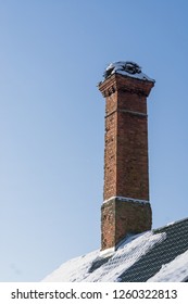 Abandoned Ruin Of Oven Chimney. Broken Furnace. Snowy Roof, Stork Slot And Blue Sky Background In The Winter