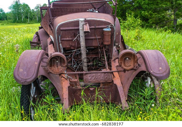 Abandoned rusted antique car in a field near Ely, Minnesota green grass ...