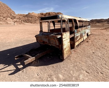 An abandoned, rusted bus in the desert of San Pedro de Atacama, Chile, surrounded by barren, rocky landscape under a clear sky. - Powered by Shutterstock