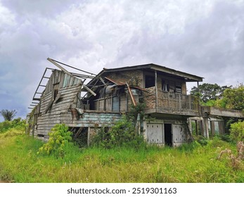 Abandoned Rustic House Amid Overgrown Vegetation Under Cloudy Sky. An abandoned rustic house stands in overgrown vegetation. The house abandoned because of vulcanic activity on the mountain