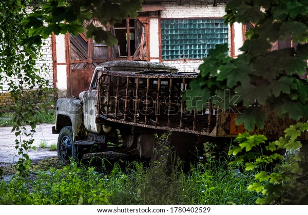 An abandoned rusty\
gas carrier in the abandoned city of Chernobyl. Selective focus.\
Truck in the bushes.
