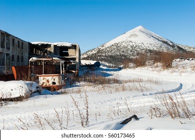 Abandoned settlement with decayed buildings and old destroyed bus in Northern Kolyma winter view