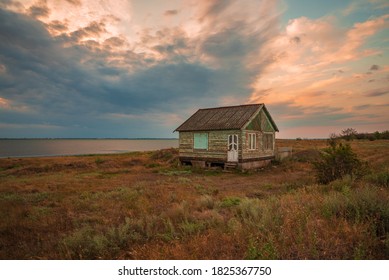 Abandoned small country house in the middle of the meadow near the lake