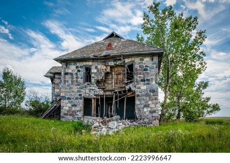 An abandoned stone house surrounded by trees on the Saskatchewan prairies outside Abernethy, SK