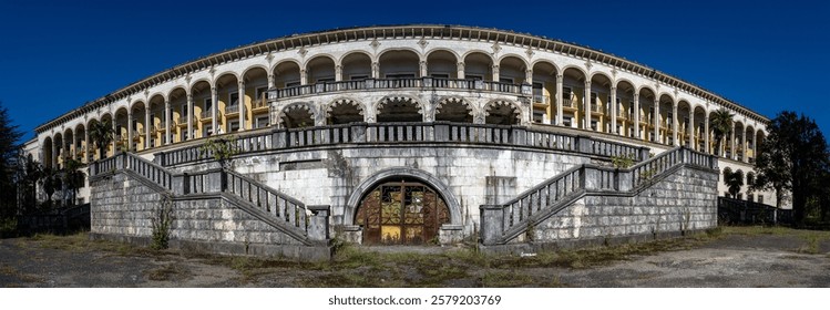 Abandoned Tskaltubo sanatorium facade featuring grand neoclassical columns, decorative arches, peeling exterior walls, reflecting architectural grandeur left to decay