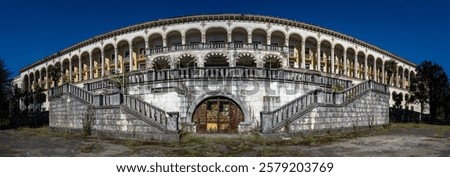 Abandoned Tskaltubo sanatorium facade featuring grand neoclassical columns, decorative arches, peeling exterior walls, reflecting architectural grandeur left to decay