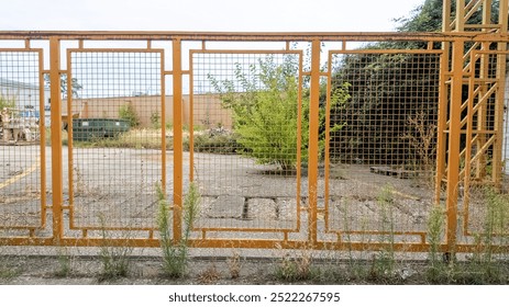 Abandoned urban lot with overgrown weeds and a rusty fence, depicting urban decay and neglect - Powered by Shutterstock