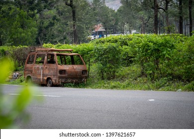 Abandoned van parked in side of hill road in a foggy bright day