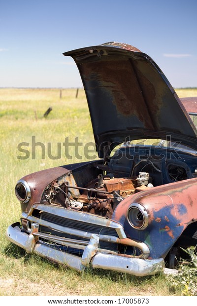 abandoned vintage\
car with popped hood in a\
field