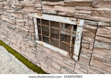 Abandoned warehouse window. Rusty grate window. Safety security protection. Light brick wall with metal grate window cover. Basement background