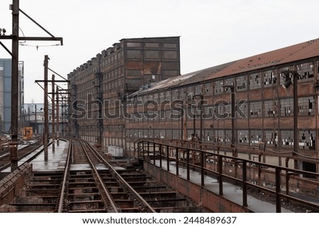 Abandoned warehouses with elevated train tracks running alongside, bleak winter Rust Belt scene, horizontal aspect
