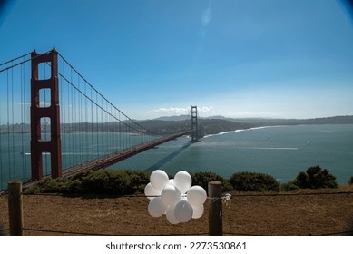 Abandoned white balloons flutter in the wind above the Golden Gate on a sunny day