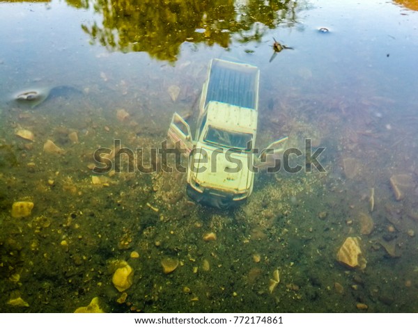 an abandoned white for wheel vehicle   inside a deep and\
clean lake 