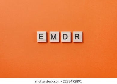 Abbreviation EMDR from wooden blocks with letters on orange background. Minimal concept of Eye Movement Desensitization and Reprocessing. Method of psychotherapy working with traumatic memories - Shutterstock ID 2283492891