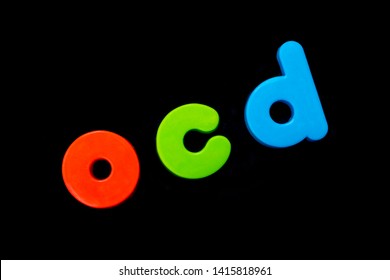 The Abbreviation OCD (Obsessive Compulsive Disorder) Spelt With Brightly Coloured Letters Over A Black Background. 