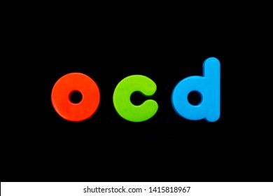 The Abbreviation OCD (Obsessive Compulsive Disorder) Spelt With Brightly Coloured Letters Over A Black Background. 