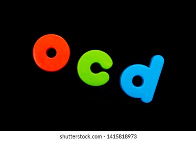 The Abbreviation OCD (Obsessive Compulsive Disorder) Spelt With Brightly Coloured Letters Over A Black Background. 