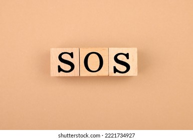 Abbreviation SOS Made Of Wooden Cubes On Light Brown Background, Top View