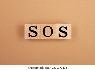 Abbreviation SOS Made Of Wooden Cubes On Light Brown Background, Top View