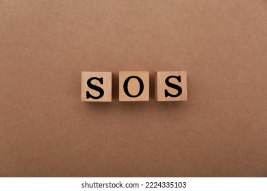 Abbreviation SOS Made Of Wooden Cubes On Light Brown Background, Top View