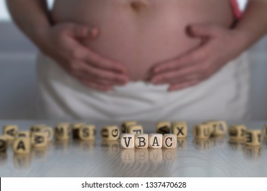 Abbreviation VBAC composed of wooden letters for Vaginal Birth after Caesarean. Pregnant woman in the background