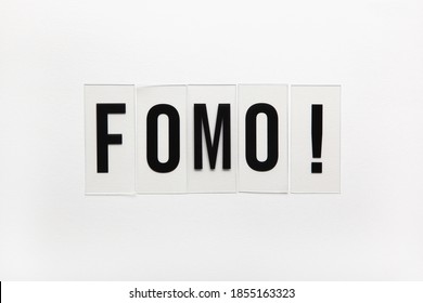 Abbreviation word FOMO on transparent plastic on white. It means Fear Of Missing Out, non-stop internet surfing. Concept social communication problem between people, digital detox. Flat lay.