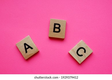 ABC Is Alphabetical Characters On A Pink Background. Wooden Alphabetical Blocks, Isolated Against A Pink Background. English Alphabet. View From Above. Words. English Language. Grammar