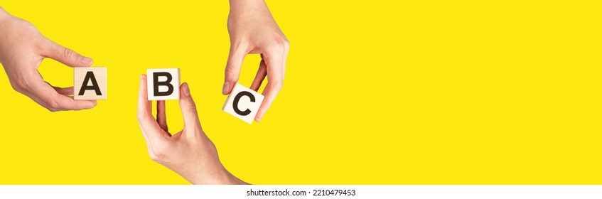 ABC Letters On Cubes In Hands On Yellow Background, Banner With Copy Space For Text. High Quality Photo