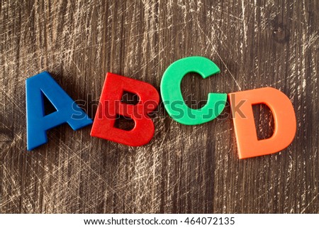  ABCD spelling from plastic letters on wooden background