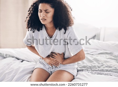 Abdomen pain, period and black woman in bed with abdominal cramps, menstruation and stomach ache. Health, medical emergency and girl with digestion problem, pms crisis and endometriosis in bedroom