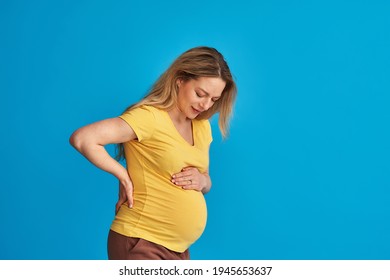 Abdominal Pain Of A Pregnant Woman On A Blue Background. Labor Pains Before Childbirth. Back Pain During Prolonged Pregnancy.kidney Failure.risk Of Miscarriage